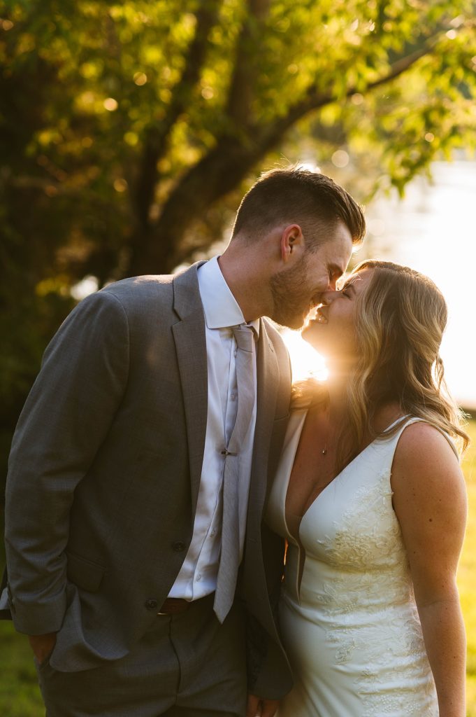 Newlyweds nuzzling noses by a lake during golden hour portraits