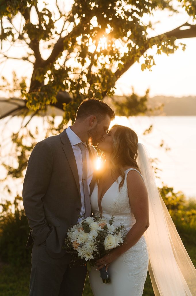 Newlyweds share a kiss with sunlight coming between them by Virginia elopement photographer