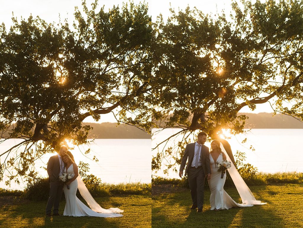 Man and woman in wedding attire walking away from lake at sunset by Hannah Louise Photography