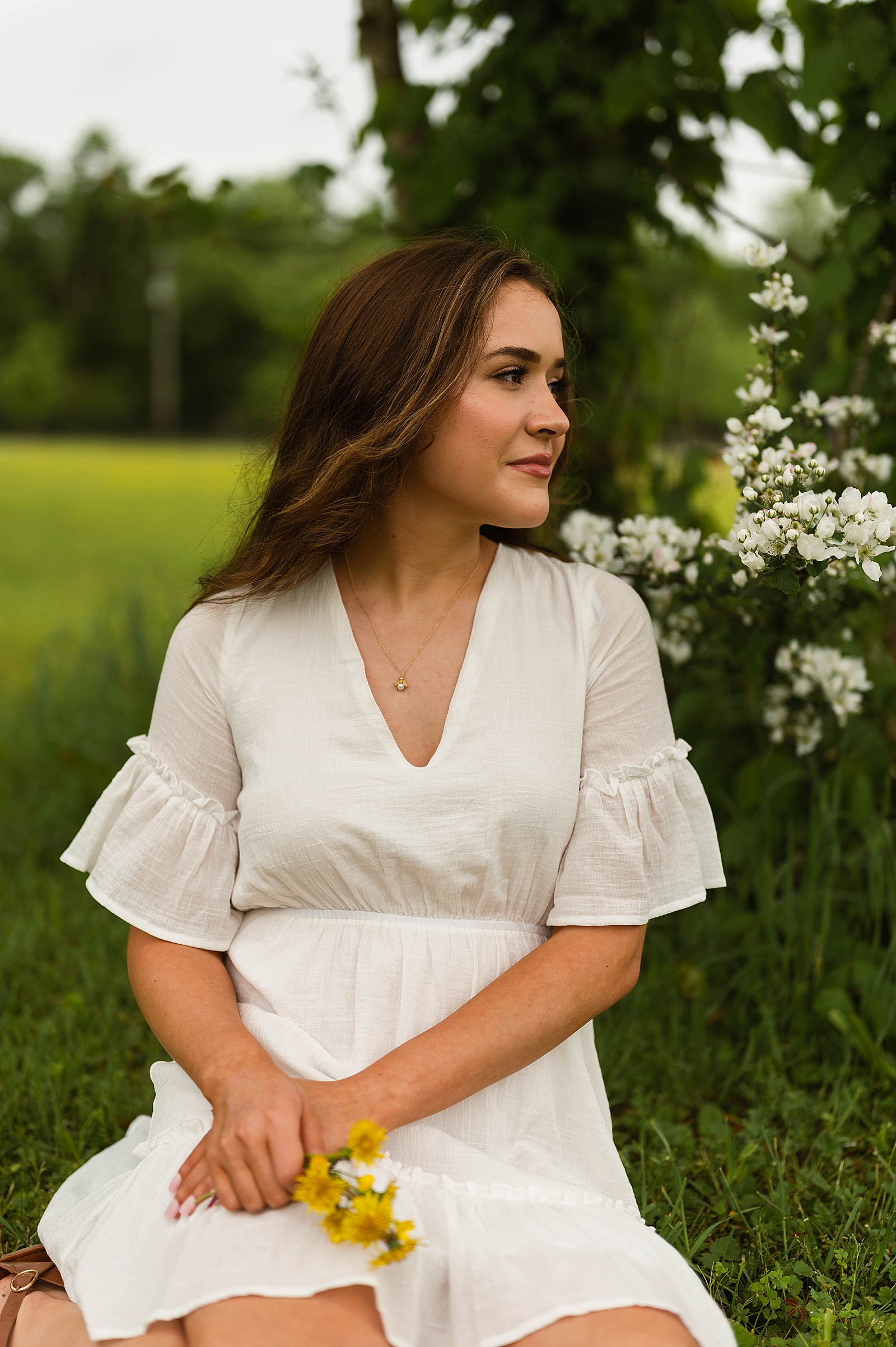 Brunette woman in white dress next to blossoming tree for Spring Flowers portraits