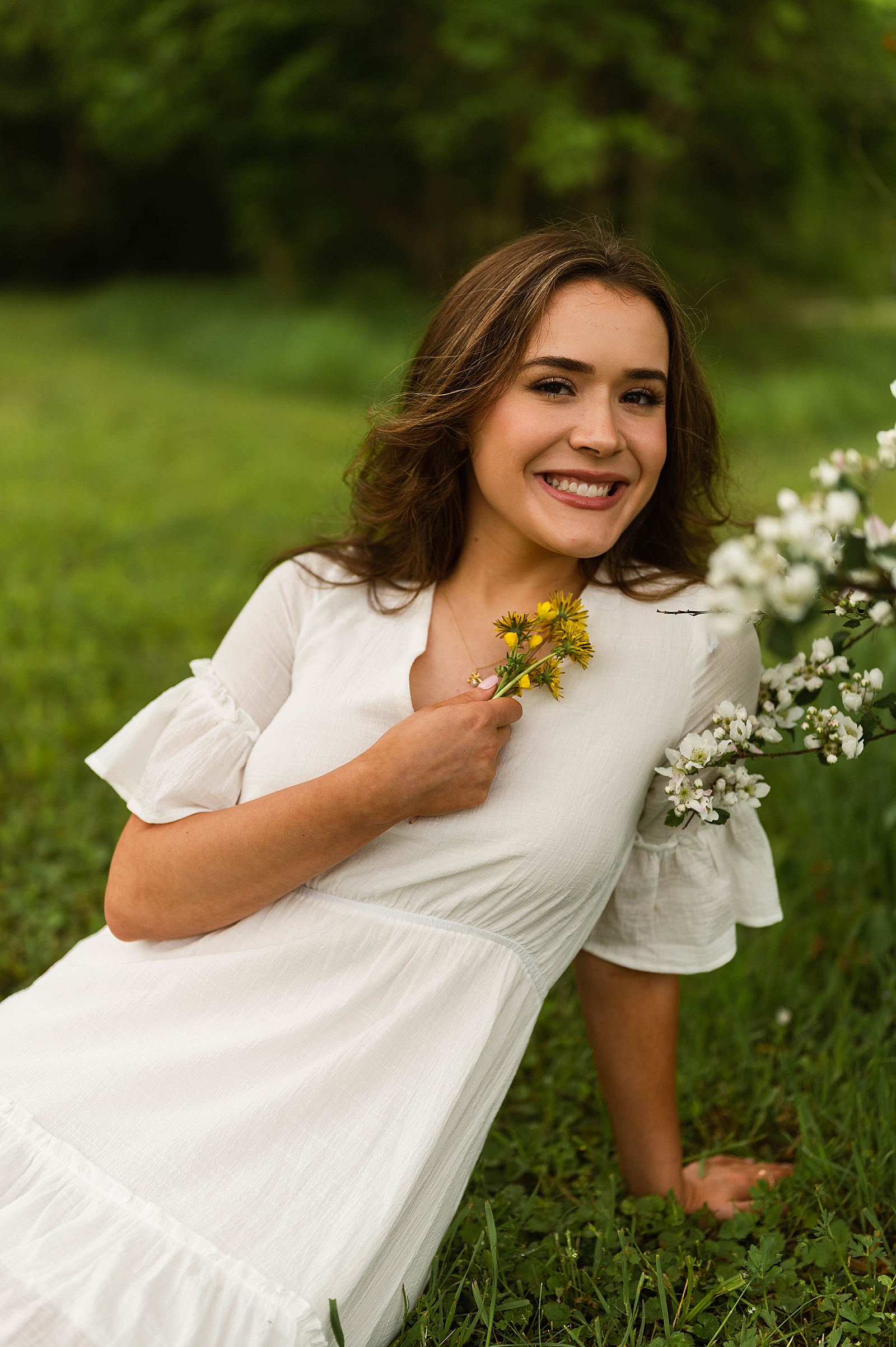 Senior holding blossoms in a field for Spring Flowers portraits