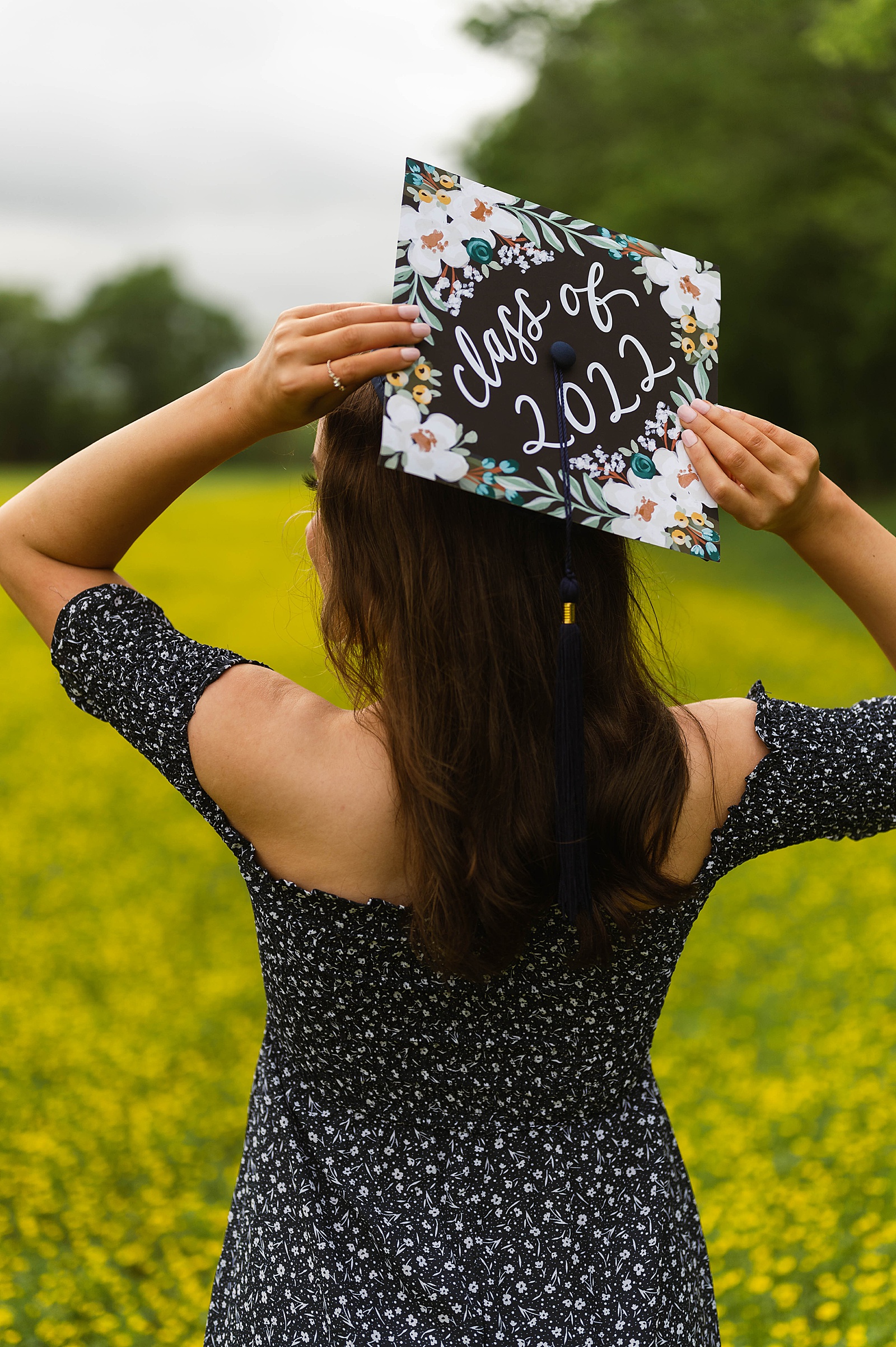 Graduating woman holding her cap in a field by Richmond senior photographer 