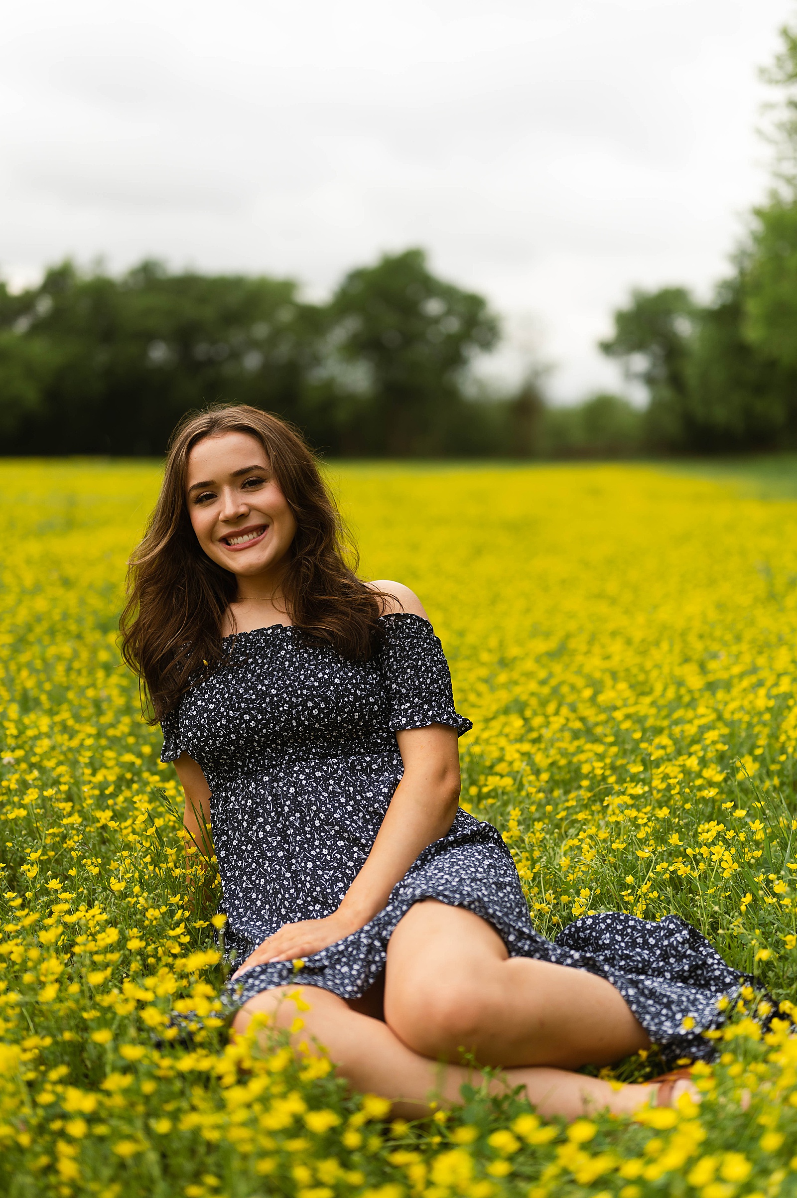 Brunette in navy dress sitting in a field for Spring Flowers portraits