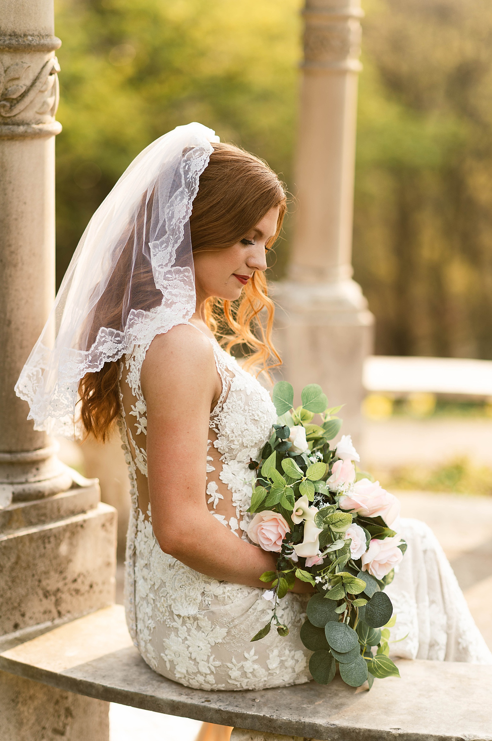 bride in lace gown and veil sitting in gazebo by Hannah Louise Photo