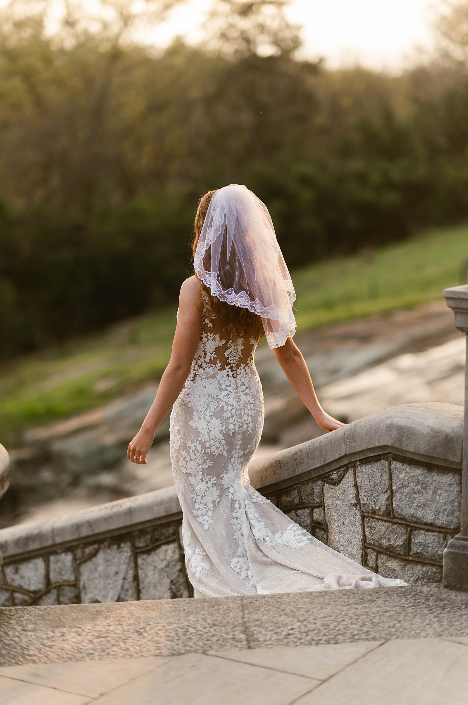 Bride in lace gown with train walking down stairs by Hannah Louise Photo