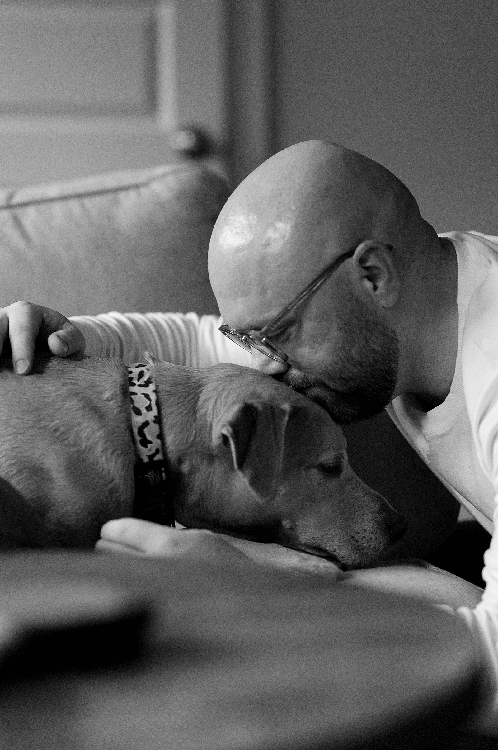Bald man kissing his dog by Hannah Louise Photo