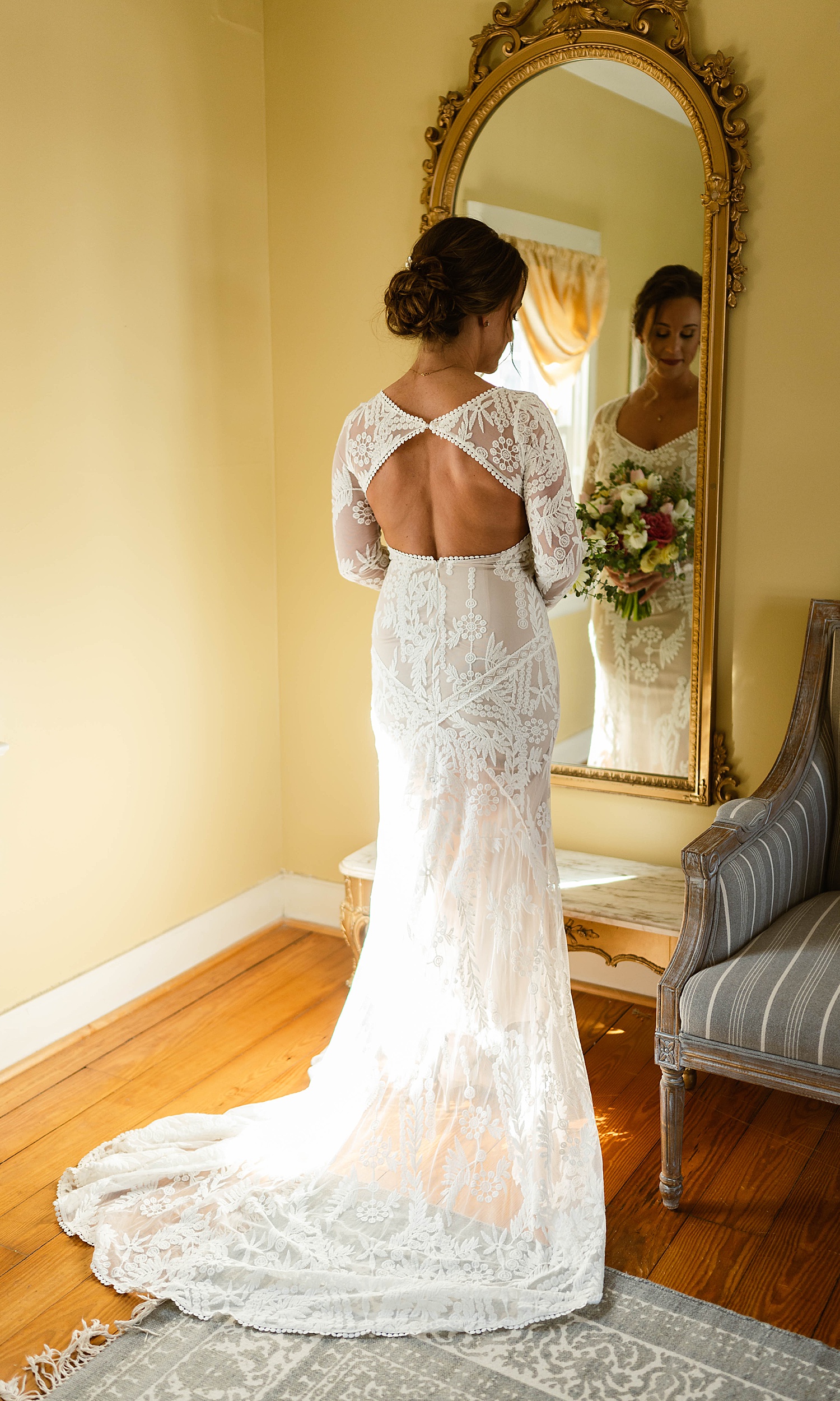 Bride in lace gown standing in front of a mirror by Hannah Louise Photo