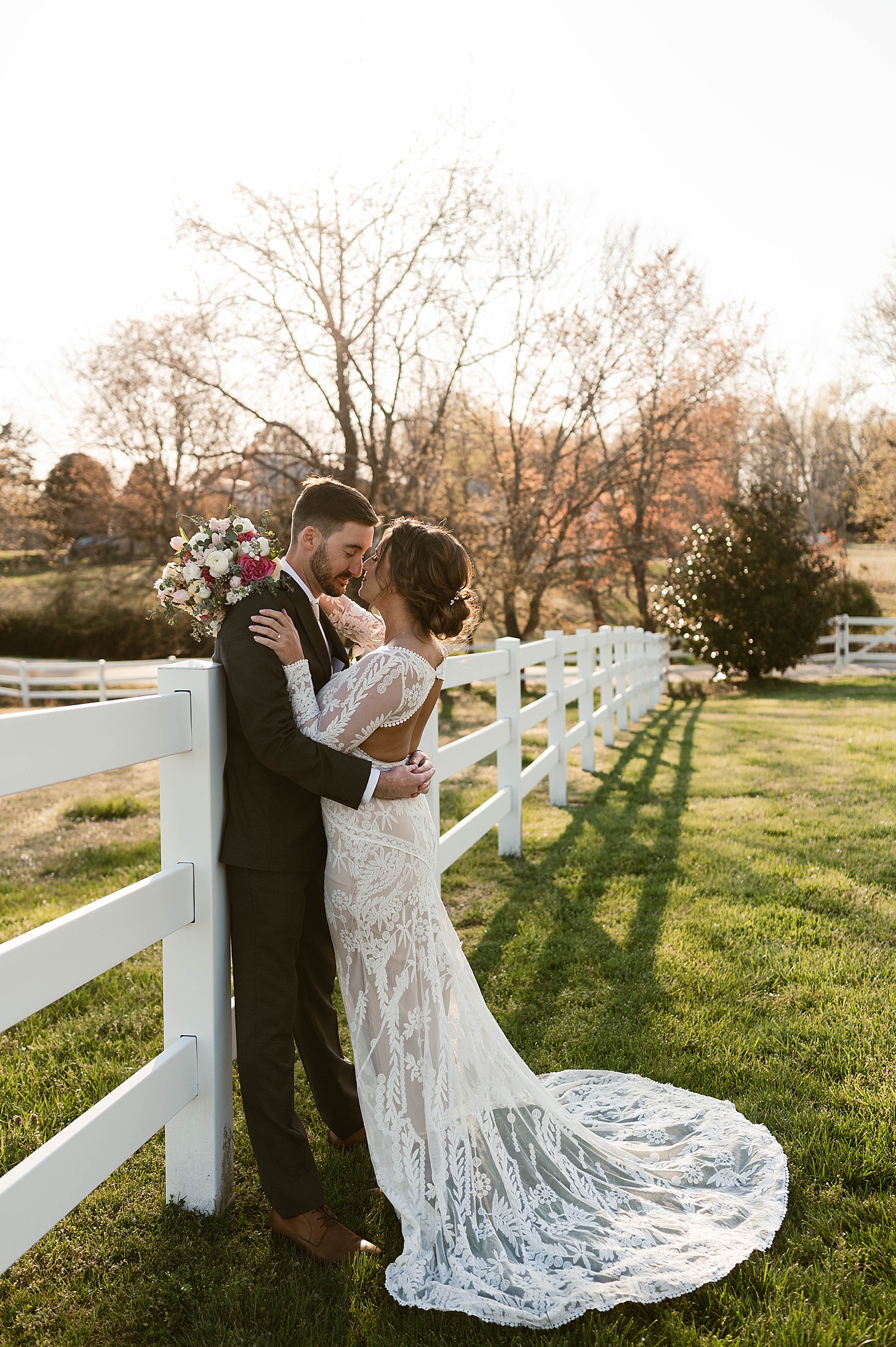 Bride and groom about to kiss by white picket fence by Hannah Louise Photo