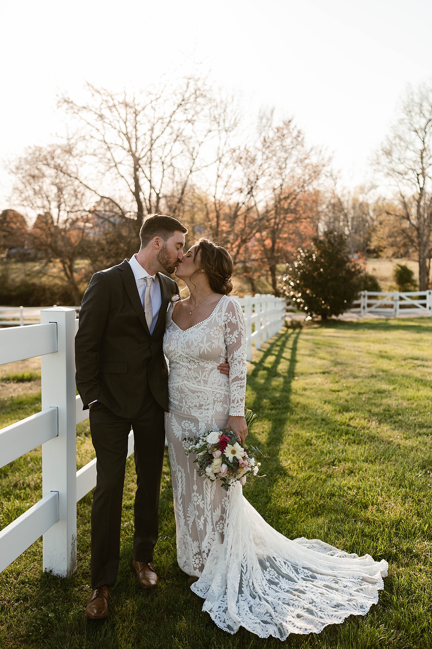 Newlyweds share a kiss by white fence by Virginia Wedding Photographer 