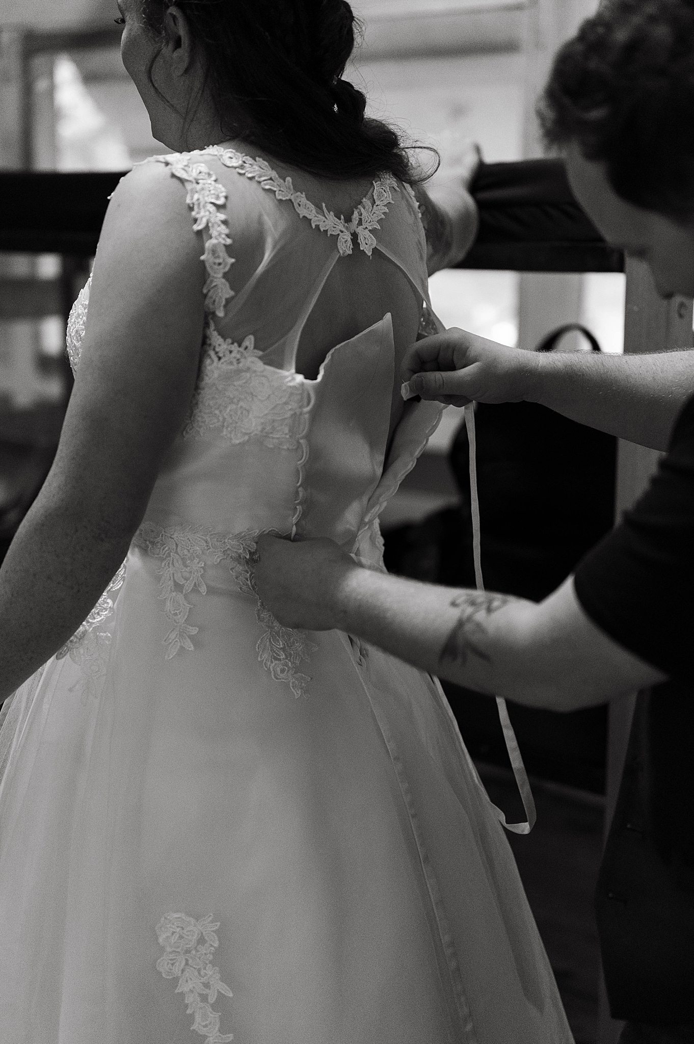 woman has help to lace up dress by Hannah Louise Photography